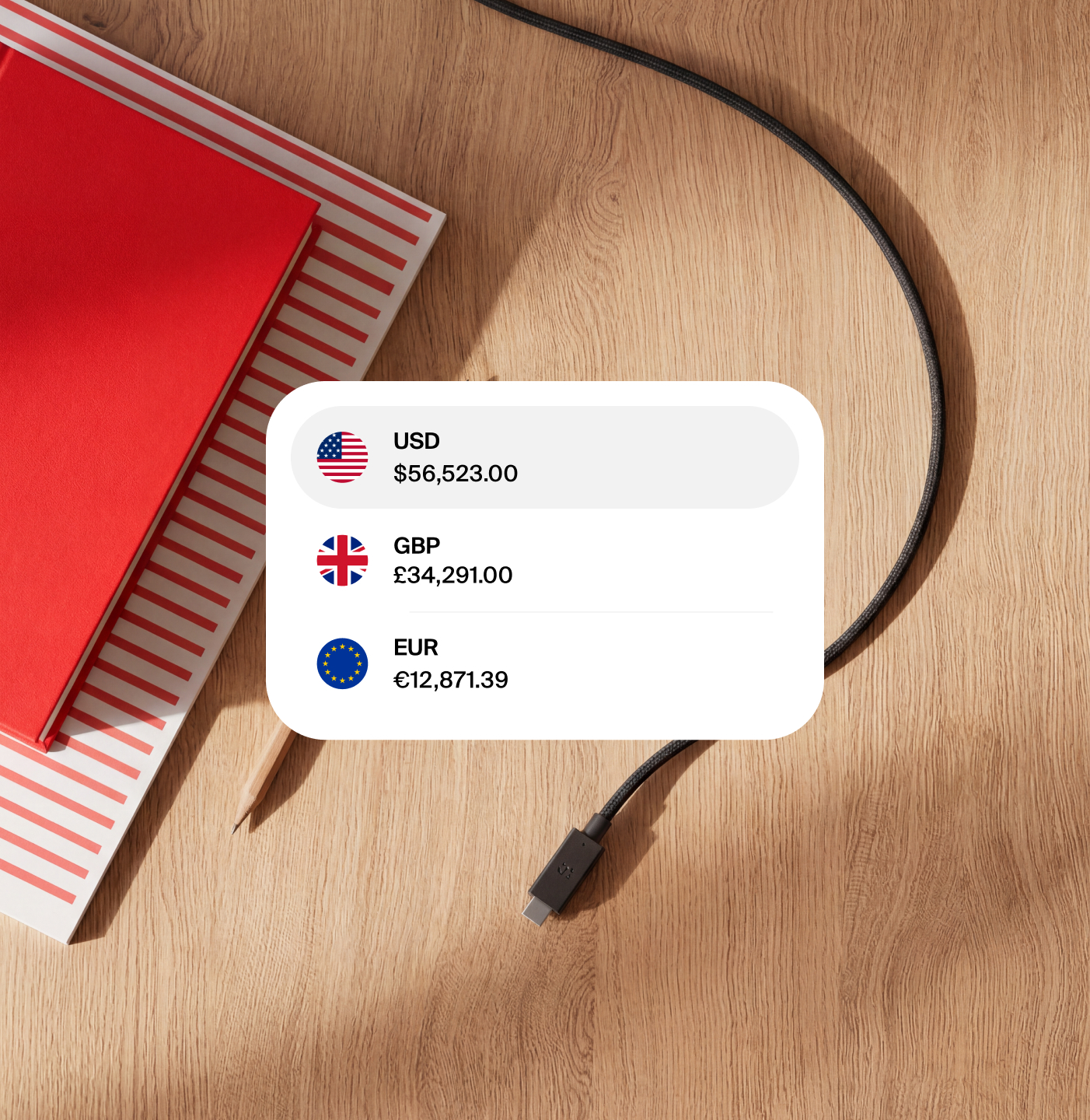 nsave multi-currency account showing USD, GBP and EUR balances beside a red notebook