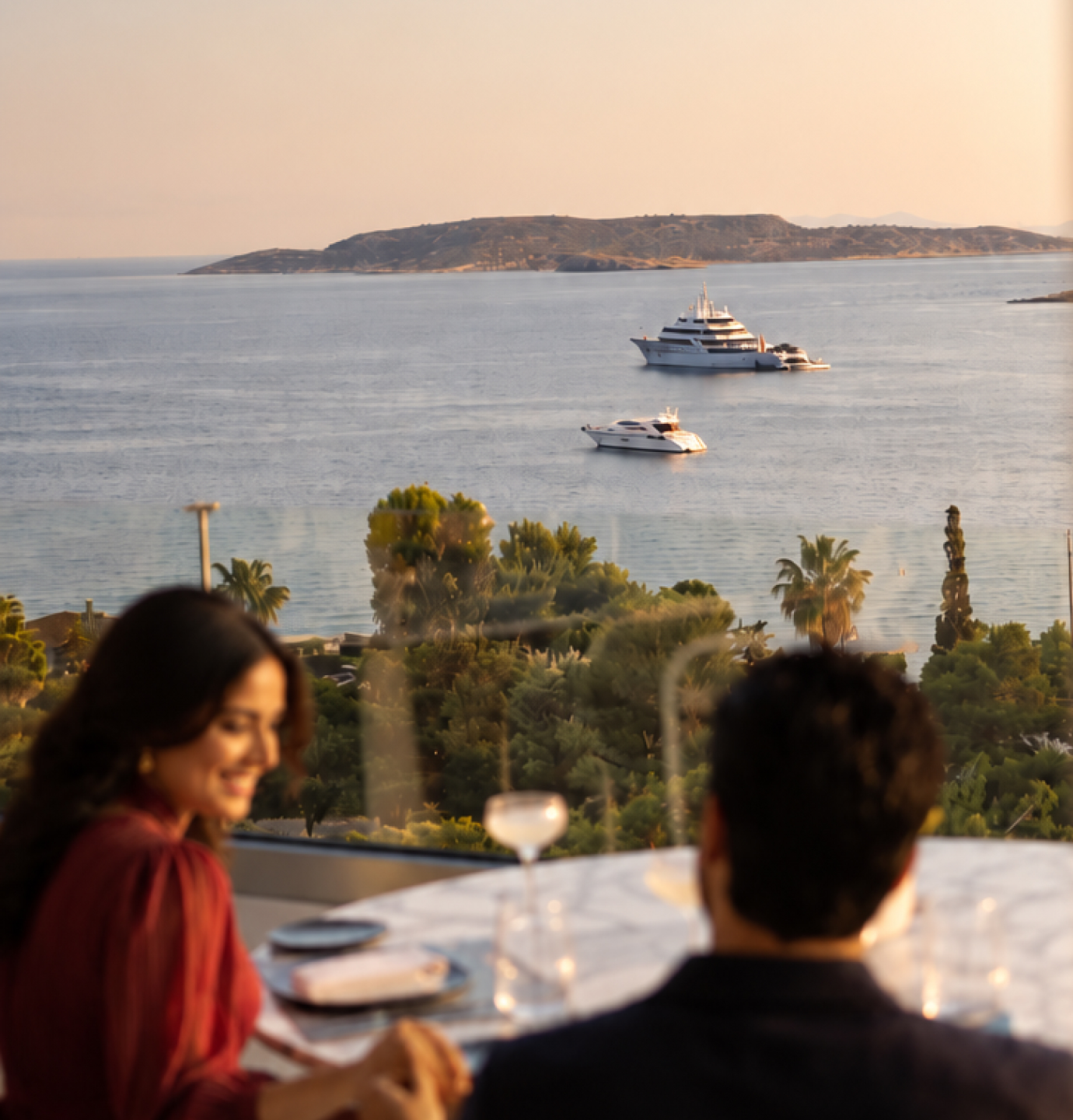 Couple dining on a terrace overlooking yachts on the sea at sunset